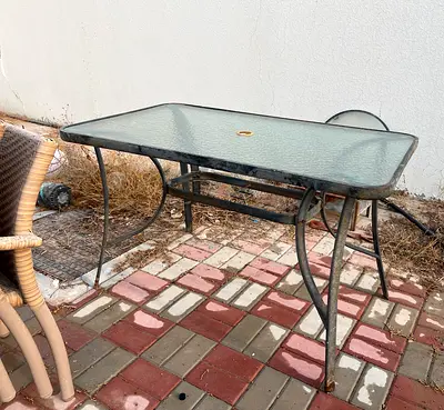 Outdoor glass-top metal patio table — used