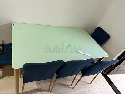 Glass-top dining table with 6 blue upholstered chairs
