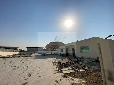 للايجار ساحة صناعية بمساحة 20,000 قدم مربع في منطقة الصجعة بالشارقة مع أرضية إنترلوك ومظلة مغطاة وكهرباء 32 كيلووات ومكتب وغرفة للعمال