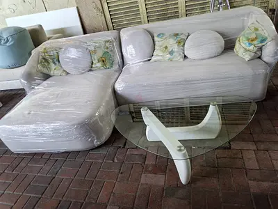 Light grey L-shaped sofa with glass coffee table - good condition