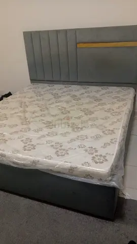 Grey upholstered double bed with headboard and matress