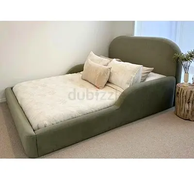Modern olive-green upholstered double bed with curved frame