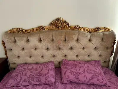 Vintage tufted king-size bed with carved gold headboard