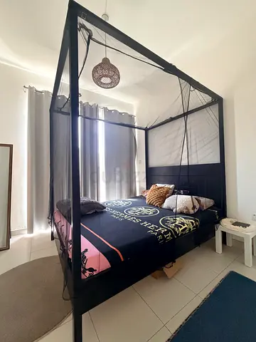 IKEA Black four-poster canopy bed frame with mosquito netting