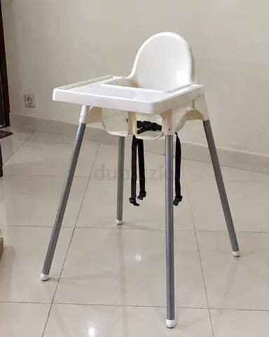Simple white baby high chair with tray and safety straps