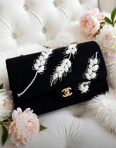 Black quilted shoulder bag with white floral embroidery