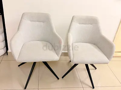 Pair of light grey fabric swivel lounge chairs with black metal legs