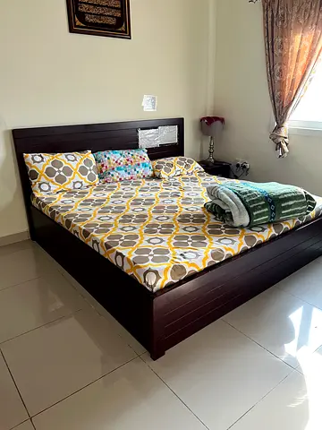 Dark wood double bed frame with mattress and bedding