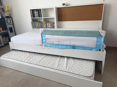 White trundle single bed with bookshelf headboard and safety rail and an extra pull out bed under