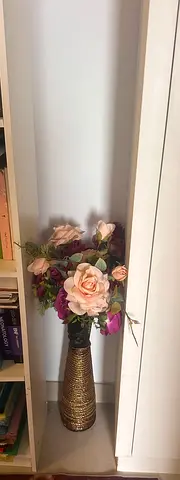 Decorative artificial flower arrangement in tall gold vase