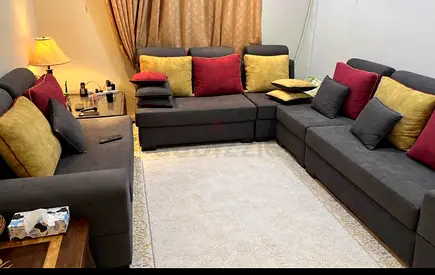 Large L-shaped grey fabric sectional sofa with cushions - good condition