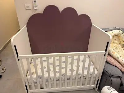 White wooden baby crib with cloud headboard and mattress