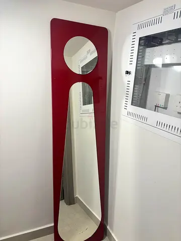 Tall red full-length mirror with circular decorative cutout