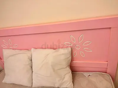 Pink wooden bed headboard with floral cutout design