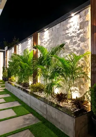 Outdoor decorative garden planter bed with Plants uplighting and stone wall beautiful view