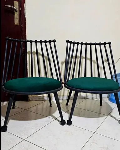 Outdoor Pair of modern black metal lounge chairs with green cushions