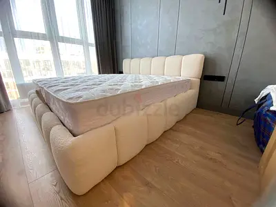 Cream upholstered queen bed with cushioned headboard and base