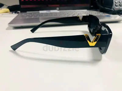 Black designer-style sunglasses with gold V detail - good condition