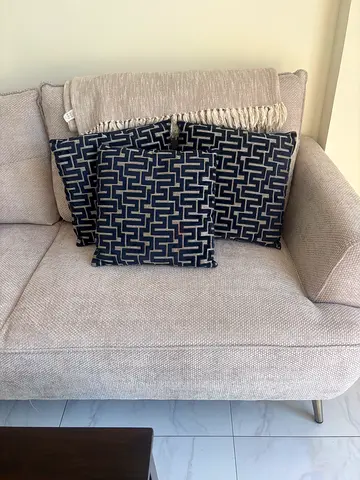 3 navy velvet cushions with beige throw over