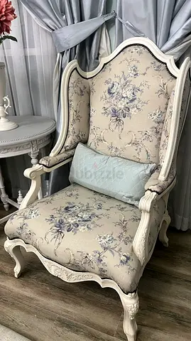 Vintage-style upholstered wingback armchair with floral fabric with a table