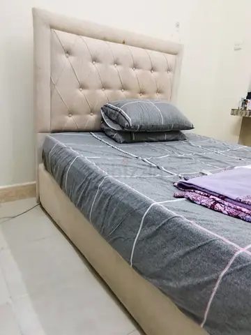 Beige upholstered single bed with tufted headboard