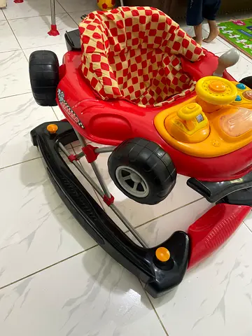 Red baby walker with activity tray and removable toy steering - used