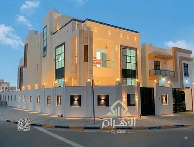 Luxury corner villa for sale in Al Helio 2 – Ajman | Two floors plus a roof | Stone facade | Situated on a corner (two-street frontage) | Located oppo