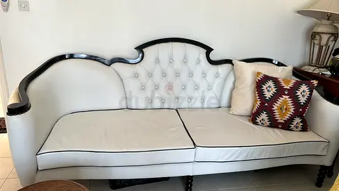 Going cheap - Vintage-style white tufted leather 3-seater sofa with dark wood trim.