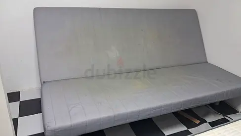 Used gray futon sofa bed with stains — needs cleaning
