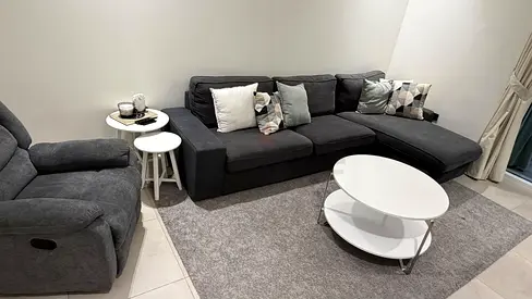 Dark grey L-shaped sofa with recliner and coffee table - good condition