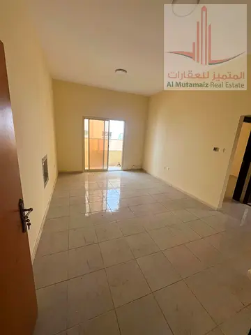 شقة غرفة وصالة للإيجار السنوي بـ23,000 درهم قرب شارع الكويت، مع حمام ومطبخ وبلكونة، صيانة على المالك ومواقف مجانية في بناية عائلات.