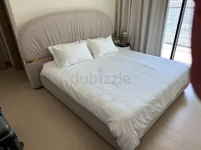 Beige upholstered queen bed with curved headboard
