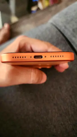 Used orange iPhone (bottom view) - very good condition, charging port visible
