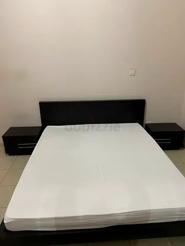 Dark wood double bed frame with headboard and matching bedside tables and dresser