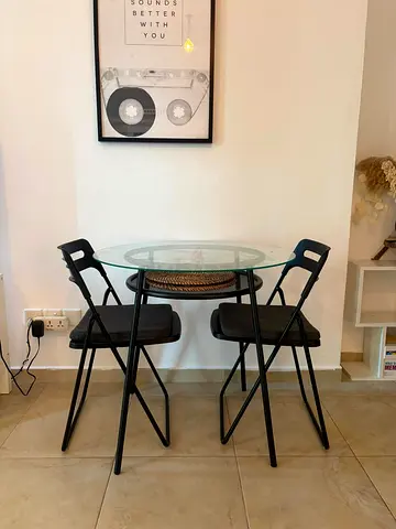 Compact glass-top dining set with 2 black folding chairs