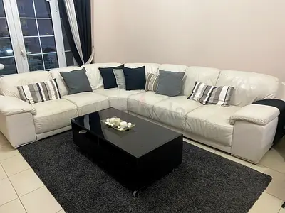 White leather L-shaped corner sofa in good condition with center table and TV console.