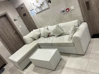 Light beige L-shaped 3-seater sofa with ottoman and cushions