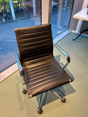 Black ribbed office chair with chrome arms, swivel (worn seat corner)