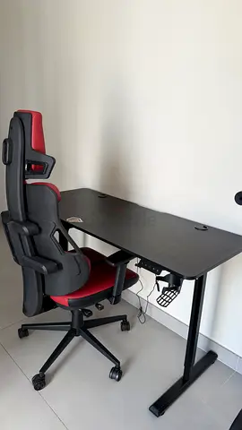 Black height-adjustable desk with red ergonomic gaming chair - good condition