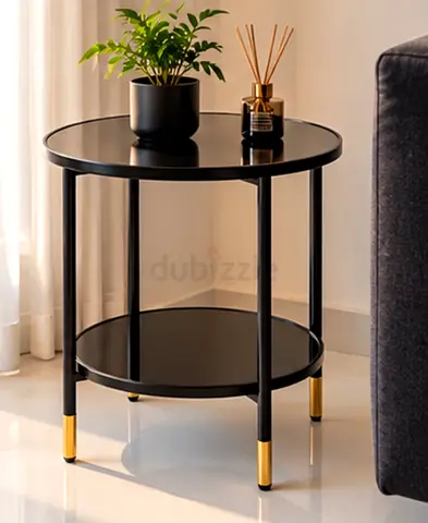Black round metal side table with lower shelf and gold accents