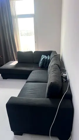 L-shaped dark grey fabric corner sofa — some wear and tear