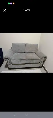 Two-seater grey fabric sofa with studded arms