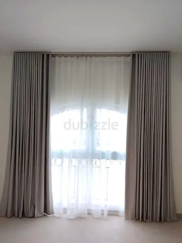 Light grey floor-to-ceiling blackout curtains with sheer voile inner panels