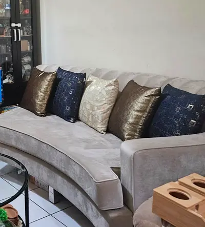 Light grey curved 3-seater sofa with cushions