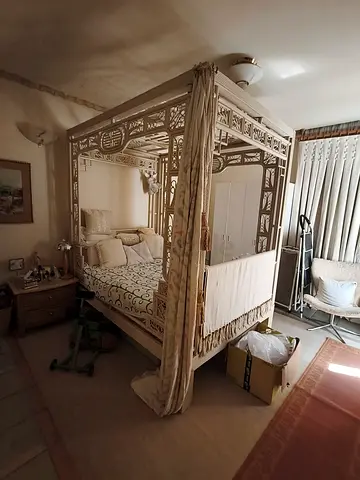 Ornate four-poster carved wooden bed with canopy