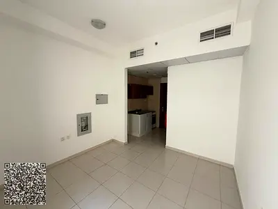 Studio for rent in Smart Tower, Al Amra area, Ajman. The unit features a separate kitchen, a balcony, and central air conditioning. The building offe