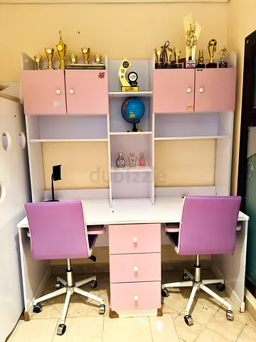 Pink and white double study desk with shelves and two chairs