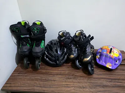 Two pairs of adjustable inline skates with helmets - good condition
