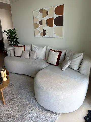 Light beige L shaped curved 4-seater sofa with cushions