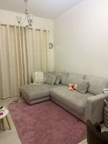 Light grey L-shaped fabric sofa in good condition